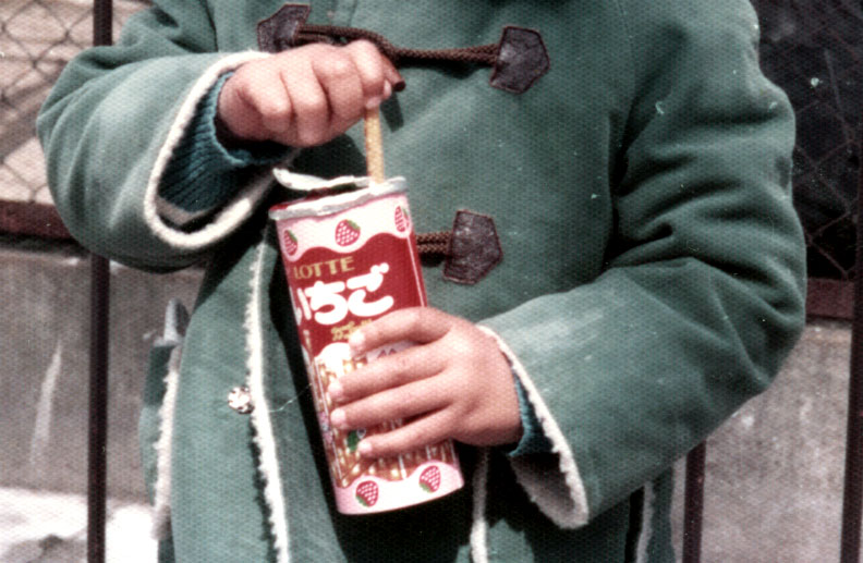 緑のコートの子がいちご菓子を手に持つ