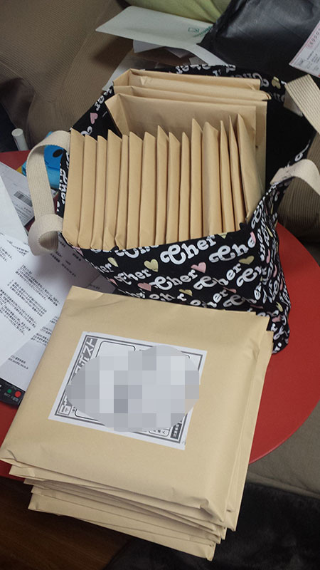 バッグに詰められた大量の茶封筒と手前に積まれた封筒