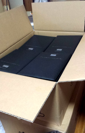 段ボール箱に詰められた4つの黒い平らなパッケージ