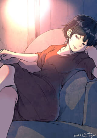 ソファでくつろぎ、こちらを見つめるショートヘアの女性。